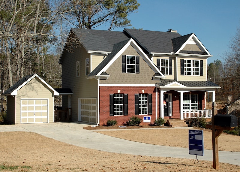 large house with for sale sign in front yard